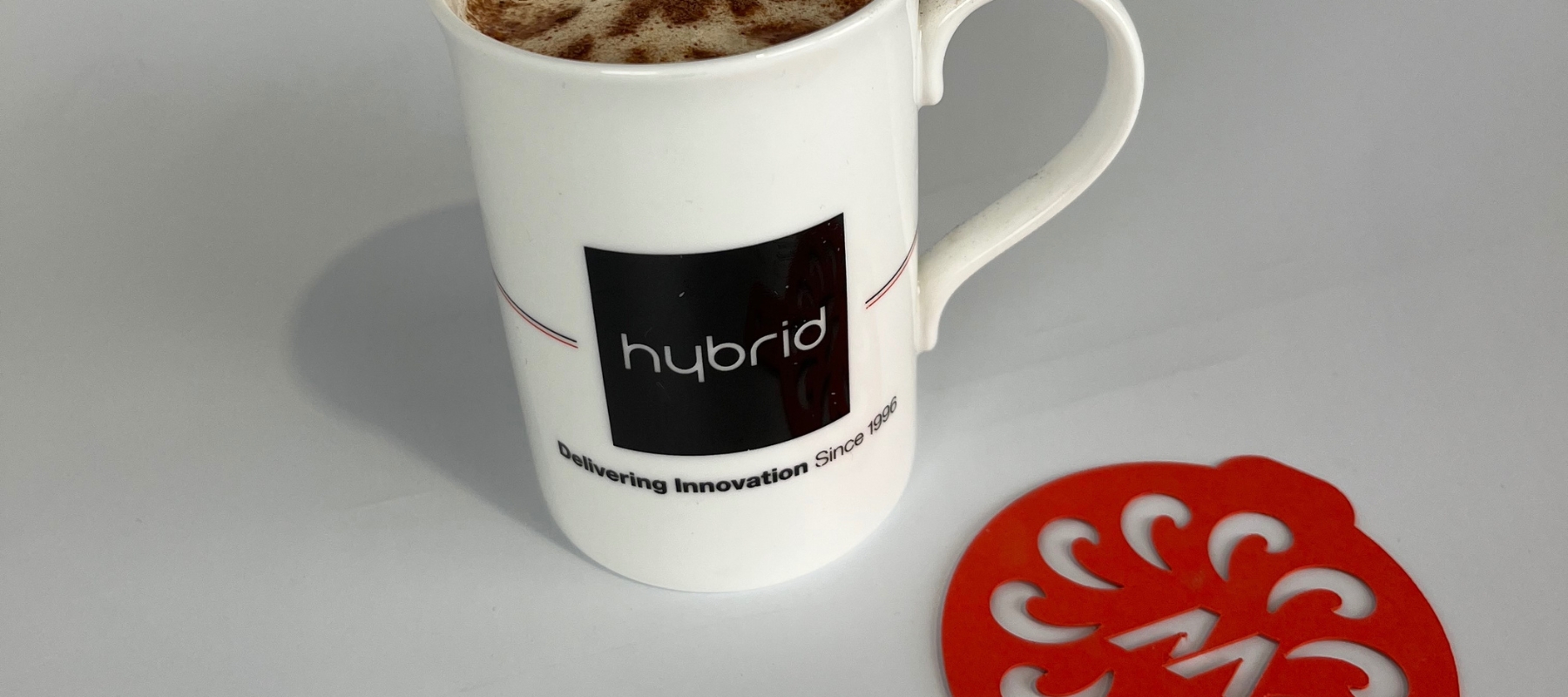 A branded mug with a cappuccino and a coffee stencil